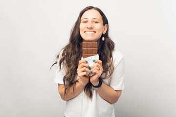 Excited young brunette woman hold chocolate bar, posing isolated on white wall background studio portrait.