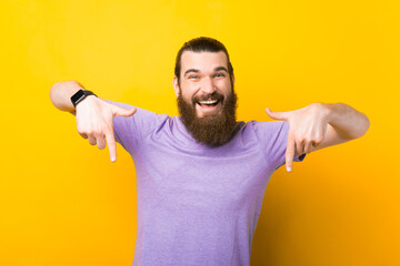 Happy carefree, friendly handsome man, give advice, indicate down link, standing yellow background