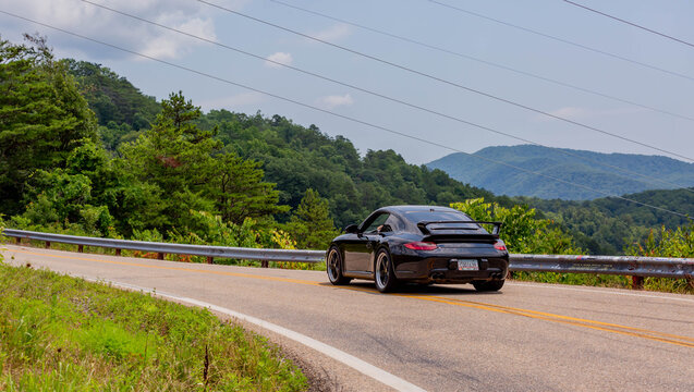 Porsche Car Driving Through Dragons Tail In North Carolina With Mountains And Trees In The Background