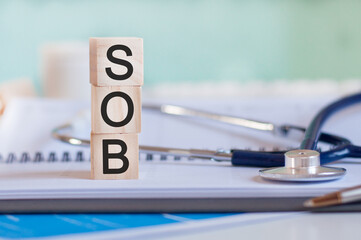 wooden block form the word SOB with stethoscope on the doctor's desktop, medical concept