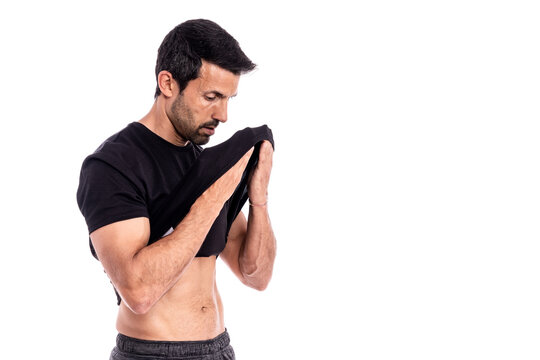 European man, caucasian, an athlete, wipes sweat from his forehead with a T-shirt. After a hard workout. Stress and fatigue. On a white background.