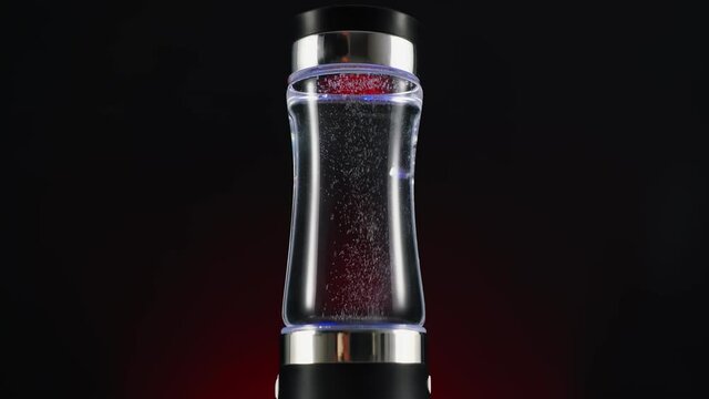 Portable device for ionization, structuring, enrichment of water alkalinity. On a red background, a dark background. for drinking water.