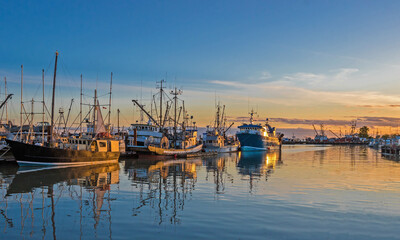 Fishing Boats in Marina and a reflection of a cloudy sky in water surface. This marina is located...