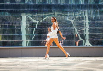 Portrait of a young beautiful brunette woman walking in summer street
