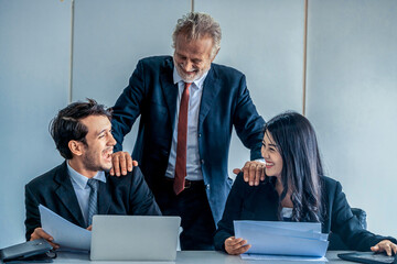 Senior caucasian manager working in office with assistance of young Asian business people and...