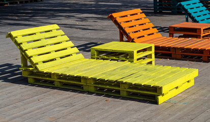 outdoor furniture and recycling theme, yellow chaise longue and table made of wood and pallets