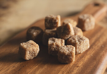 A brown cane sugar cube on a wooden cutting board.