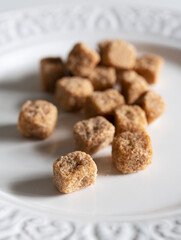 Brown cane sugar cubes on a white plate.