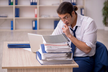 Young male employee and a lot of work in the office