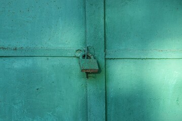 one big old iron green padlock hanging on a metal door
