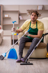 Young male contractor wearing prickly wreath on head cleaning th