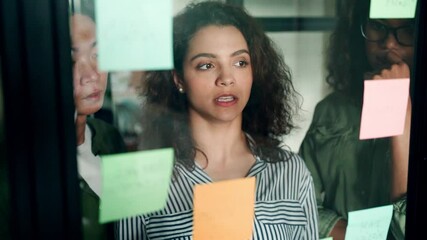 Young happy multiethnic diverse young professional creative team group students talking brainstorming discussing startup project at modern office desk looking at sticky notes on glass. Slow motion.