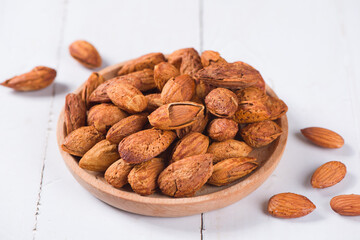 Delicious roasted sweet almonds nuts on wood background