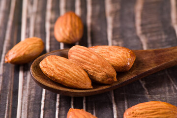 Delicious roasted sweet almonds nuts on wood background