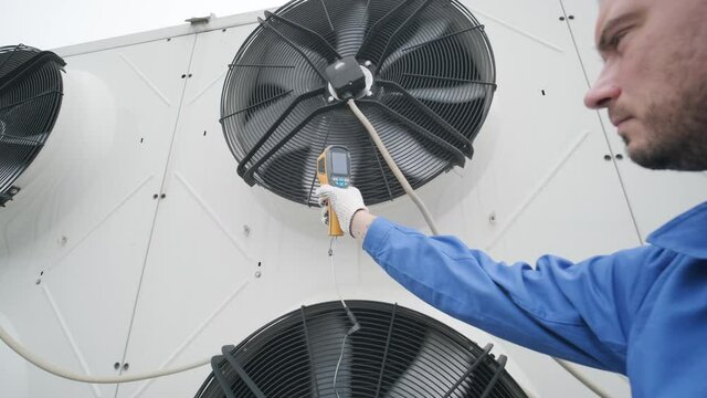 Technician uses a thermal imaging infrared thermometer to check the condensing unit heat exchanger
