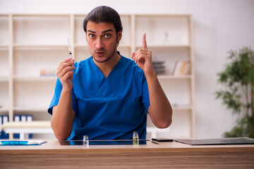 Young male doctor holding syringe in the clinic