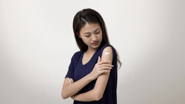 Young beautiful asian woman feel pain in arm after receiving the vaccine. She was worried and stressed that there would be side effects. She tried to massage her aching arm.