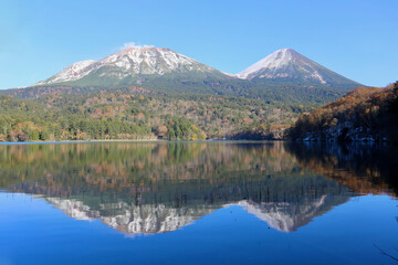 雪化粧した雌阿寒岳と紅葉が水面に映るオンネトー