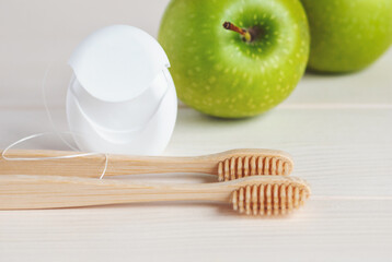 Bamboo toothbrushes, green apples and dental floss, closeup