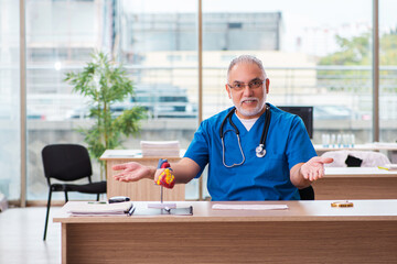 Old male doctor cardiologist working in the clinic