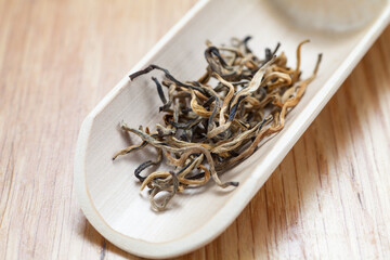 Yunnan black tea in a bamboo shovel on table. Close-up.
