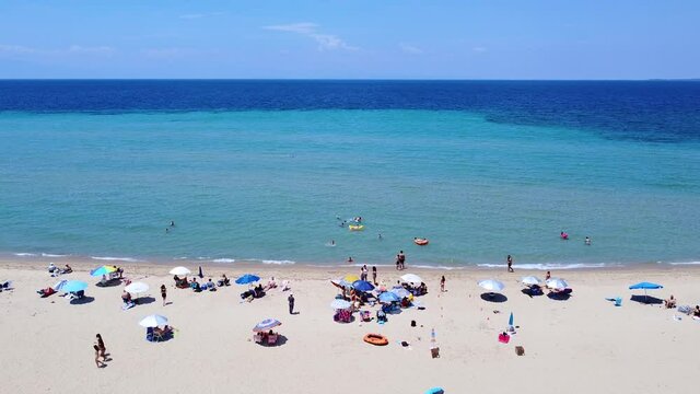 People on the sandy beach and blue clear sea spending the weekend. Aerial view 