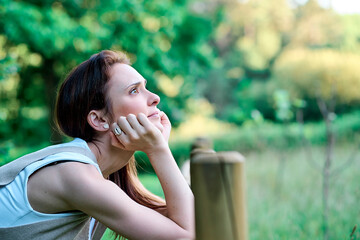 Thoughtful 35 year old millennial woman in field on sunset profile vacation