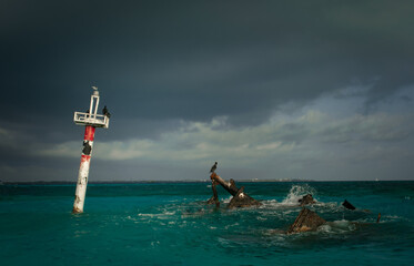 An almost completely sunken boat and lighthouse in ocean.