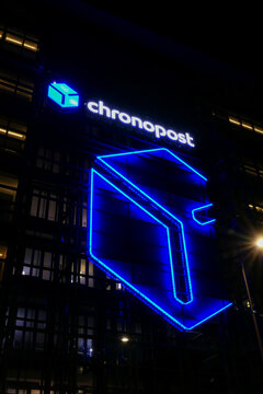 Paris, France. July 10. 2021. Neon light sign then night on building with the sign of a parcel delivery company. Chronopost logo.