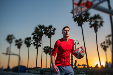 Basketball player training basketball on a court in Venice Beach.