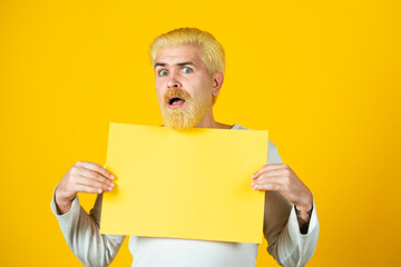 Man holding a blank sheet of paper, isolated on yellow background.