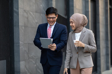 Young business muslim woman and business man colleague walking and discussing outside the office....