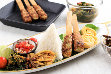 Nasi Campur Bali. Popular Balinese Meal of Rice with Various Side Dish, Served Together. This Menu Contains Ayam Sisit, Sate Lilit, Saute Papaya Leaf, and Sambal Matah.