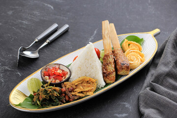 Nasi Campur Bali. Popular Balinese Meal of Rice with Various Side Dish, Served Together. This Menu Contains Ayam Sisit, Sate Lilit, Saute Papaya Leaf, and Sambal Matah.