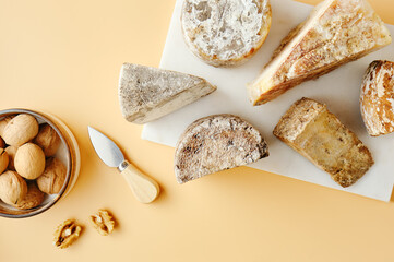 Various pieces of aged cheeses on a board and walnuts