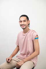 Fototapeta premium Portrait photo young happy Asian hipster man with colorful bandage laughing happily after received covid-19 vaccine from free vaccine campaign for prevent coronavirus outbreak. Asian people portrait.