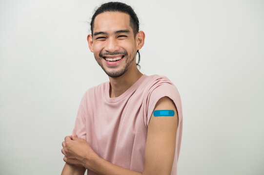 Portrait photo young happy Asian hipster man with colorful bandage laughing happily after received covid-19 vaccine from free vaccine campaign for prevent coronavirus outbreak. Asian people portrait.