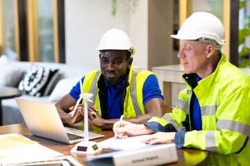 Two engineers African american engineer and caucasian electrician wearing white hard hat working on laptop computer at workplace office. clean and green alternative energy concept.