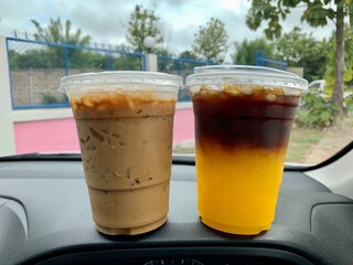 Plastic cup ice coffee on dash board of the car.