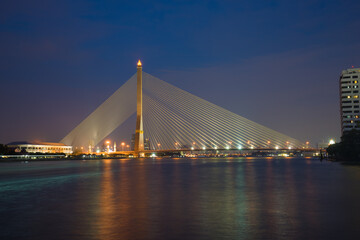 Fototapeta na wymiar View of the cable-stayed bridge Rama VIII Bridge on the Chao Phraya river in the evening illumination. Bangkok, Thailand