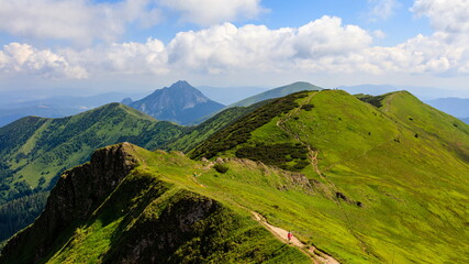 Fototapeta na wymiar Green mountain ridge in nice weather, with blue sky and white clouds. Mala Fatra