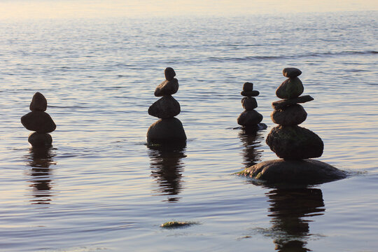 Stones in the water are stacked in pyramids. Image on the topic of balance and peace of mind