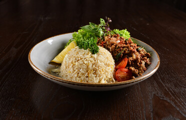 Thai style egg fried rice with spicy minced meat quorn and sliced of lemon asian vegetarian menu on wood table