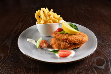 deep fried golden chicken meat / quorn vegetarian / fish fillet seafood steak with French fries and vegetables in lemon creamy sauce on wood background western menu