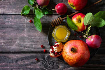 Religion image of Rosh hashanah (jewish New Year holiday) concept. Traditional symbols: honey, apples and pomegranate on a dark rustic table. Top view flat lay background. Copy space.