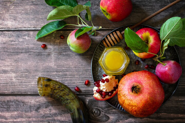 Religion image of Rosh hashanah (jewish New Year holiday) concept. Traditional symbols: honey, apples and pomegranate on a dark rustic table. Top view flat lay background. Copy space.