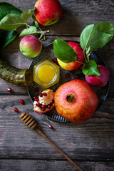 Religion image of Rosh hashanah (jewish New Year holiday) concept. Traditional symbols: honey, apples and pomegranate on a dark rustic table. Top view flat lay background.