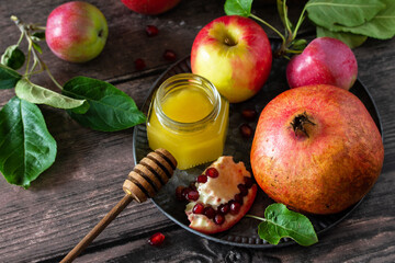 Religion image of Rosh hashanah (jewish New Year holiday) concept. Traditional symbols: honey, apples and pomegranate on a dark rustic table.