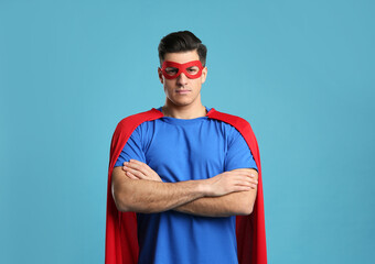 Man wearing superhero cape and mask on light blue background © New Africa