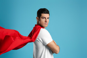 Man wearing superhero cape on light blue background